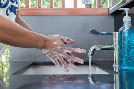 Man is washing his hands in a sink sanitizing the colona virus for sanitation and reducing the spread of COVID-19 spreading throughout the world, Hygiene ,Sanitation concept.の写真素材
