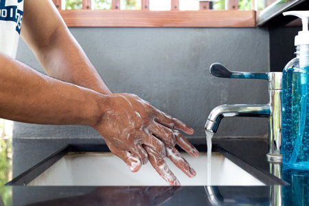 Man is washing his hands in a sink sanitizing the colona virus for sanitation and reducing the spread of COVID-19 spreading throughout the world, Hygiene ,Sanitation concept.の写真素材