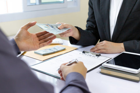 Businessmen give dollars to bribe employees in signing contracts to buy illegal land and real estate, Business fraud and social injustice, corruption and bribery concept.の写真素材