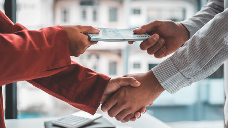 Shaking hands with congratulations on an evil plan, Businessmen give dollars to bribe employees in...