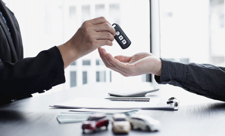 Car sales representative or sales manager submits a car key to a client who has approved financial...