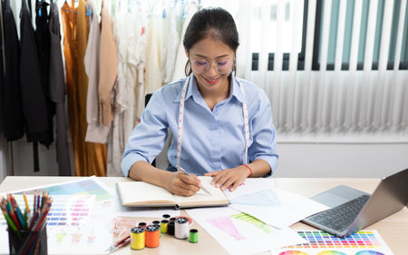 Fashion designers are working in workshops with laptops and design drawings on their desks, Creating a new collection of clothes, Creation of the work of the designer.の写真素材