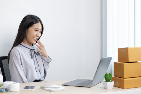 Young woman was happy after receiving an order from an internet customer, Entrepreneurs selling products online or doing freelance work at home concept.の写真素材