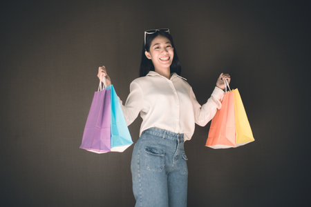 Text input box, Brown background, Young women carrying colorful shopping bags, Happy to buy products concept.の写真素材