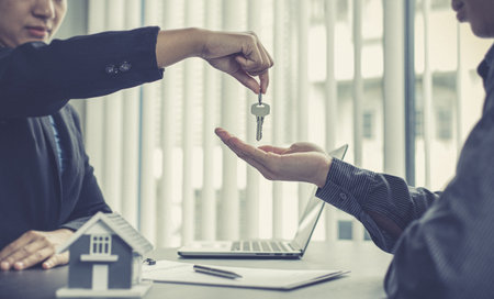 Sales manager or real estate agent holds the key handing it to the customer after signing the house purchase contract with home insurance, Trading of mortgages and insurance concept.の写真素材