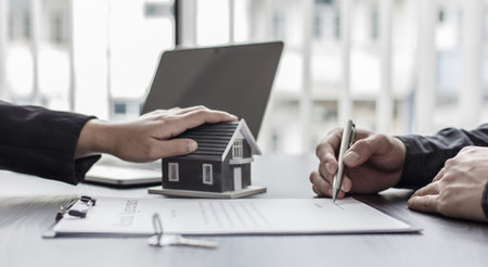 Real estate agent or sales manager has proposed terms and conditions to customers who sign house purchase agreements with insurance, Agreement to sign the purchase contract concept.の写真素材