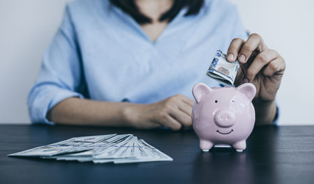 Businessman's hand holds the money in the piggy bank for saving money for future use, saving money...