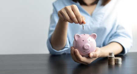 Young woman is saving money and calculating the income and expenses of the house due to the poor economic situation which makes saving money, Save money concept.の写真素材