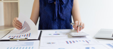 Accounting businessmen are calculating income-expenditure and analyzing real estate investment data, She works on a desk has graphs and calculators with laptop, Financial and tax systems concept.の写真素材