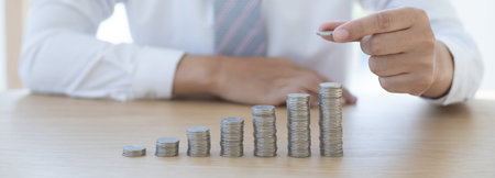 Businessman putting money on stacking coin that shows a graph the financial growth profit of...