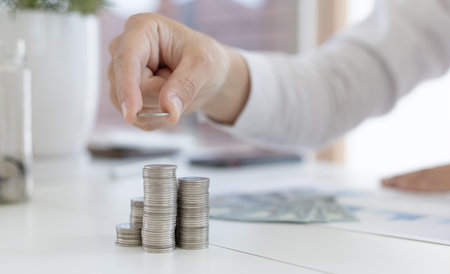 Businessman putting money on stacking coin that shows a graph the financial growth profit of business investment, Money management for use when needed,  saving money and investment conceptの写真素材