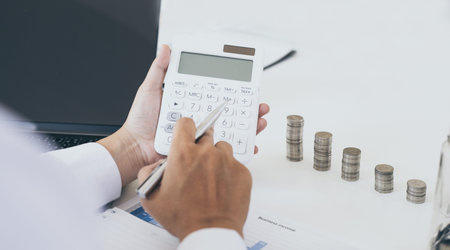 Dollar coins arranged in a slope graph, Blurred image of a business man pressing a calculator,...