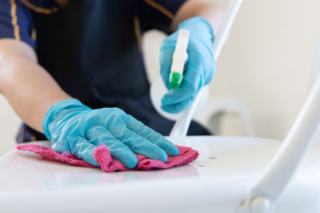Close up employees' hands were wiping the Chair legs or table legs to clean after the customers finished their meal, Using cleaning solutions or using alcohol to kill germs in the restaurant.の写真素材