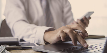 Financial businessmen use laptop and smart phone to analyze marketing strategies and real estate data to reduce company taxes for their customers, Accounting and Tax concept.の写真素材