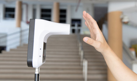 Young man used his palm to touch the sensor of the thermometer temperature using a non-contact infrared thermometer, Body temperature measurement device to prevent COVID-19 virus.の写真素材