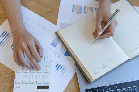 Head of accounting is recording the company's financial growth statistics using graphs as a reference for reviewing and analyzing the results, Taking notes and analyzing data graphs in office.の写真素材