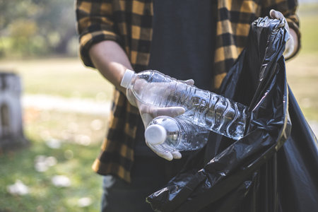 Male volunteers carry water bottles or plastic bags that have fallen in the park put them in trash cans, Environmental protection or volunteering for charity, Waste disposal through recycling.の写真素材