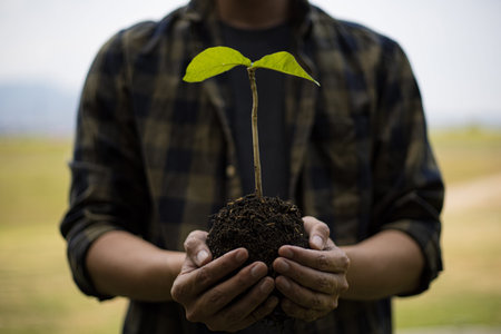 Young man was holding a seedling to prepare to plant a tree, Preserving or loving the environment or...