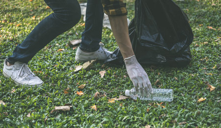 Male volunteers carry water bottles or plastic bags that have fallen in the park put them in trash cans, Environmental protection or volunteering for charity, Waste disposal through recycling.の写真素材