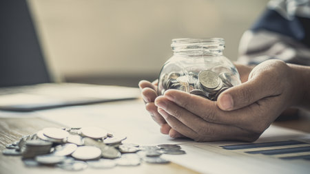 Young businessman uses both hands to protect Piggy bank or coins, Investments or business people working in finance and accounting, Saving money, reducing production costs concept.の写真素材