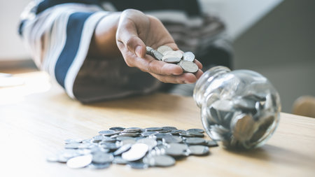 In the hand of a woman holding a coin or money and put it into the piggy bank, Saving money for future use, saving money, Money management systematically, Spending money like maturity concept.の写真素材