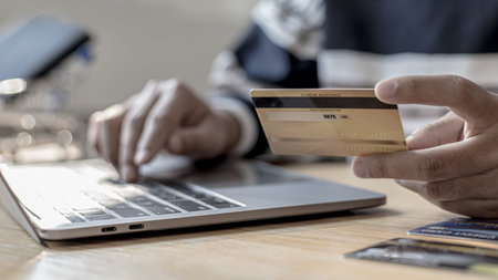 Woman's finger presses a keyboard and holds a credit card to register for payment or online...