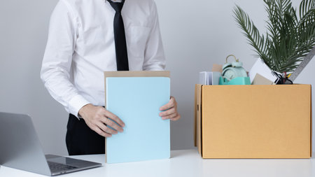 Put the work equipment in the office in a large brown box, Businessmen are keeping work documents and personal belongings due to resignation or being fired, termination of employment.の写真素材
