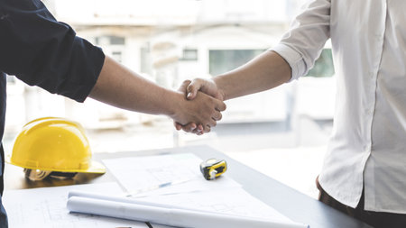 Men shake hands after the deal is done, Architects and engineers join hands to congratulate them after the building site meeting is completed, Symbol of friendship in business of both parties.の写真素材