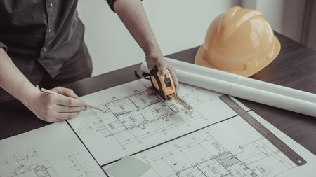 Architectural building design and construction plans with blueprints, Young man was designing a...