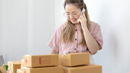 Young woman selling products online was talking on the phone to receive an order from a customer who called and wrote down the list in a notebook, New kind of business for young, Sell online.の写真素材