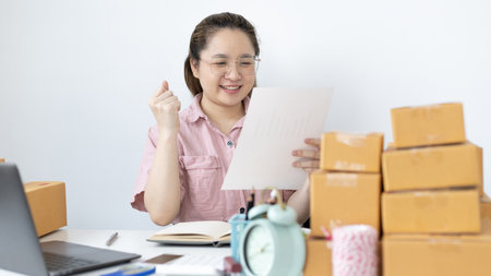 Young woman was happy after receiving an order from an internet customer, New business style for young people working at home and owning businesses, Sell online or Online sell concept.の写真素材