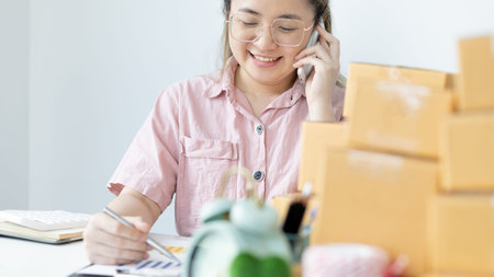 Young woman selling products online was talking on the phone to receive an order from a customer who...