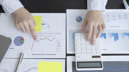 Young Asian businesswoman presses a calculator to calculate income tax and corporate income in a...