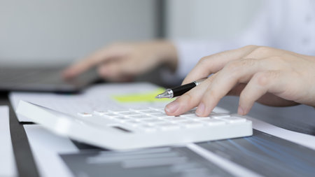 Young Asian businesswoman presses a calculator to calculate income tax and corporate income in a...