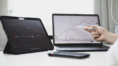 Investors sit and watch graphs of stock market data and watch the world market chart change,...