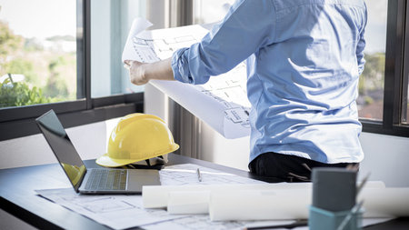 Architectural building design and construction plans with blueprints, Young man was designing a...