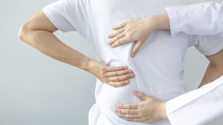 Physical therapy, Female physiotherapist treats back pain for a male patient attending a...