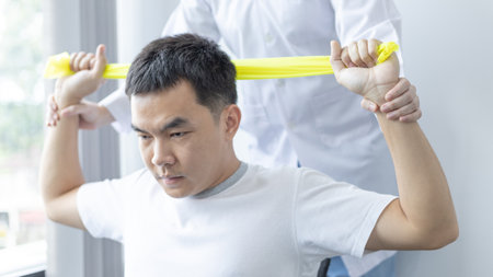 Physical therapy, Female physiotherapist uses an elastic band to test the arm injury of a male patient attending in clinic, Bone arrangement, Non-surgical medical treatment, Medical techniques.の写真素材