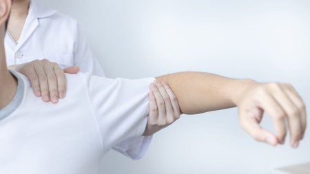 Physical therapy, Female physiotherapist treats arms and shoulders pain for a male patient attending...
