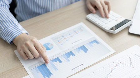 Asian business women are analyzing graphs, financial statistics and calculating corporate returns in...