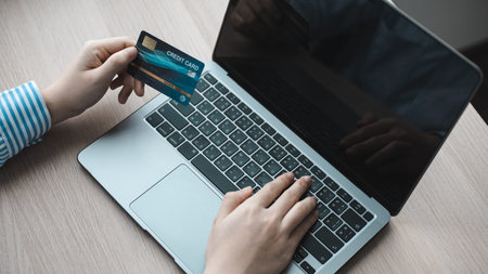 Woman's finger presses a keyboard and holds a credit card to register for payment or online...