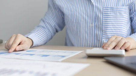 Asian business women are analyzing graphs, financial statistics and calculating corporate returns in...