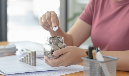 Woman puts a coin dollar in a jar, Saving money for future growth and knowing how to manage your...