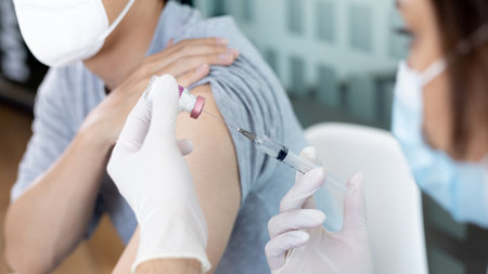 Doctor vaccinating patient, vaccination against new strains of virus, Doctor holding a syringe, Antivirus vaccination for people, Covid-19, Doctor vaccinating male patient in clinic or hospital.の写真素材