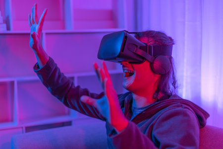 Man wearing virtual reality glasses is playing a 3D game with excitement, Remote Controller, VR, Future games, Gadgets, Technology, Red and blue background, VR game concept.の写真素材