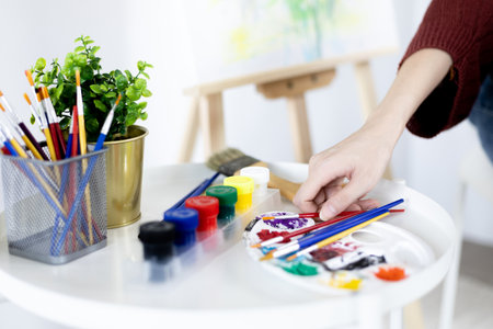 Female artist painting on canvas, Artist studio interior, Draw with watercolor, Drawing supplies , Painting and creativity, Use a brush to draw a pattern by stripes, Artwork, Using Paint Brush.の写真素材