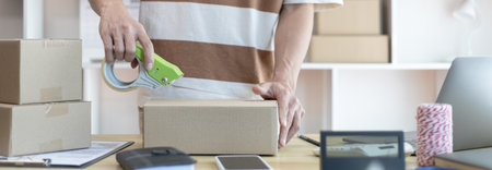 Man is packing in the mailbox to prepare to deliver it to the customer, Working at home and owning businesses, Online shopping SME entrepreneur, packing box, Sell online, freelance working.の写真素材