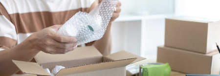 Man is packing in the mailbox to prepare to deliver it to the customer, Working at home and owning businesses, Online shopping SME entrepreneur, packing box, Sell online, freelance working.の写真素材
