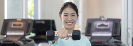 Beautiful and shapely Asian woman working out in the gym, Play exercise machine treadmill, Dumbbell,...