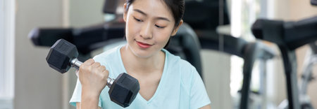 Beautiful and shapely Asian woman working out in the gym, Play exercise machine treadmill, Dumbbell,...